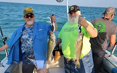 Three fishermen aboard More Gooder Fishing Charters on Lake Erie, with two showcasing their Walleye catch on July 22, 2023.
